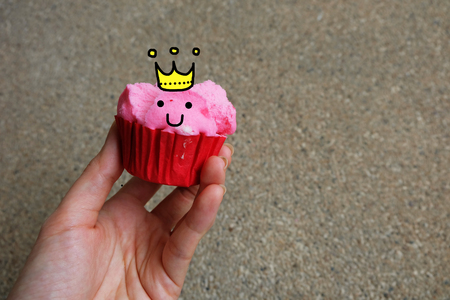 Close Up Steamed Cup Cake, Hand hold Pink Steamed Cup Cake with Smile Face on Concrete Background Great For Any Use.の写真素材