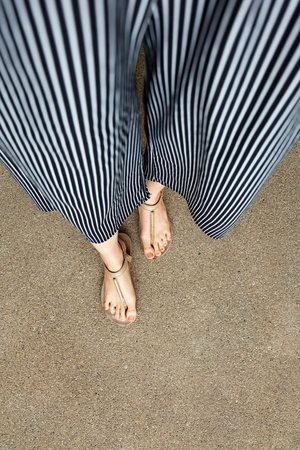 Feet Woman Wear Sandals and Black Pants. Female Standing on The Cement Background Great For Any Use.