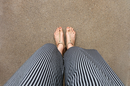 Feet Woman Wear Sandals and Black Pants. Female Standing on The Cement Background Great For Any Use.の写真素材