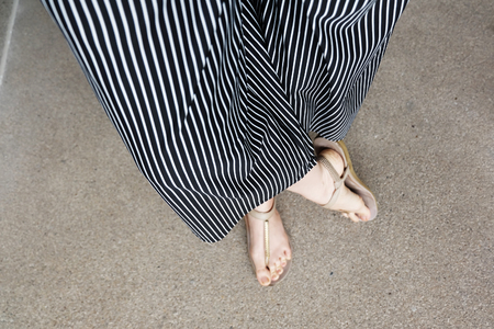 Feet Woman Wear Sandals and Black Pants. Female Standing on The Cement Background Great For Any Use.の写真素材