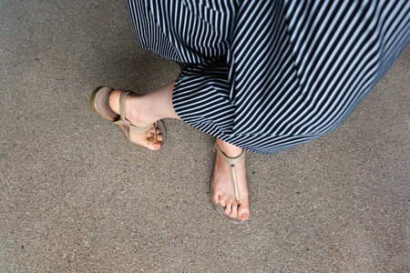 Feet Woman Wear Sandals and Black Pants. Female Standing on The Cement Background Great For Any Use.
