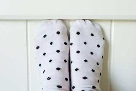 Close Up Feet Wearing White Polka Dot Socks in Bedroom Background Great For Any Use.の写真素材