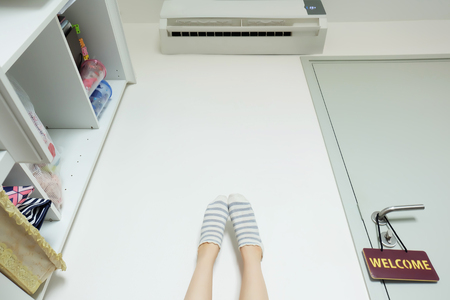 Slim Legs. Woman's Legs in Striped Yellow socks Near Door with Label Welcome on White Wall at Home Great for Any Use.の写真素材