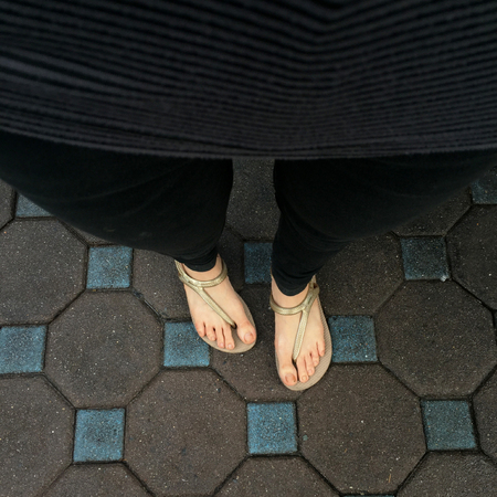 Selfie Woman's Feet Wearing Sandals and Black Jeans on Tile Background Great For Any Use.の写真素材