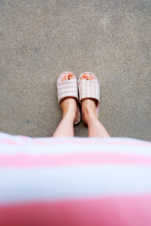 Girl Standing in Sleepwear and Pink Checkered Slippers with Holding Pink Pillow on Floor Background Great for Any Use.の写真素材