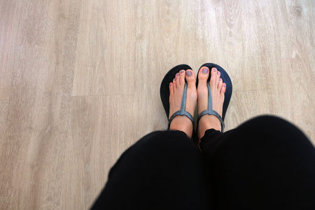 Girl Legs and Feet Wear Black Sandals on Wooden Background Great for Any Use.