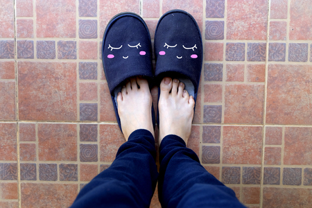 Female Legs in Blue Slippers. Woman in Smile Face Slippers Idea Concept on Tile Background Great for Any Use.の写真素材