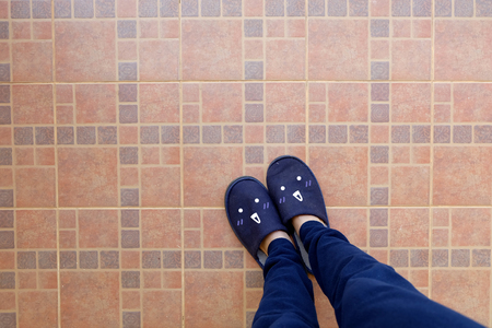 Female Legs in Blue Slippers. Woman in Smile Face Slippers Idea Concept on Tile Background Great for Any Use.の写真素材