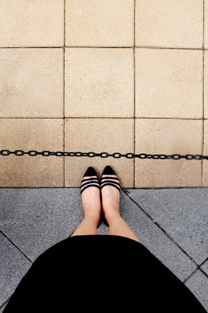 Female Wear Black Dress and Black Shoes Woman Standing on The Tile Background Great for Any Use.の写真素材