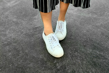 White Sneakers Shoes. Woman is Legs in White Sneaker and Pants on the Concrete Street Background Great for Any Use.の写真素材