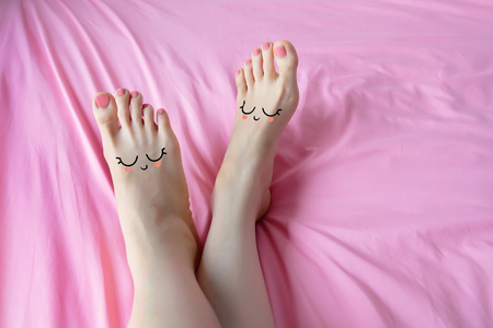 Smiley Face Emotion Barefoot. Beautiful Female Feet on Pink Fabric Bedroom Background Great for Any Use.の写真素材