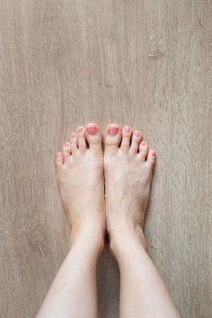 Beautiful Woman Legs and Feet. Close Up Female Barefoot On Wooden Floor Background Great for Any Use.の写真素材
