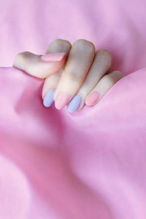 Beautiful colorful Nail Polish. Female Hands with Pink Nails Manicure on Pink Fabric Background Great for Any Use.の写真素材