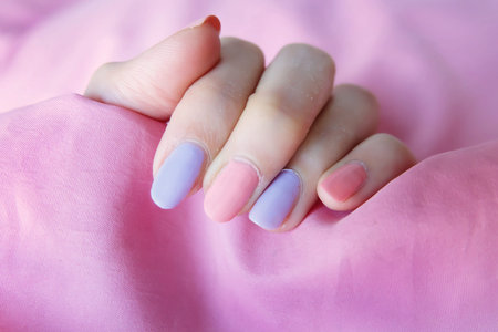 Beautiful colorful Nail Polish. Female Hands with Pink Nails Manicure on Pink Fabric Background Great for Any Use.の写真素材