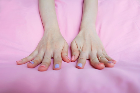Beautiful colorful Nail Polish. Female Hands with Pink Nails Manicure on Pink Fabric Background Great for Any Use.の写真素材