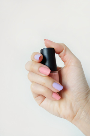 Close Up Hands with Pink Painted Nails. Beautiful Pink Nail Manicure with Pink Bottle in Woman is Hand on White Background Great for Any Use.の写真素材