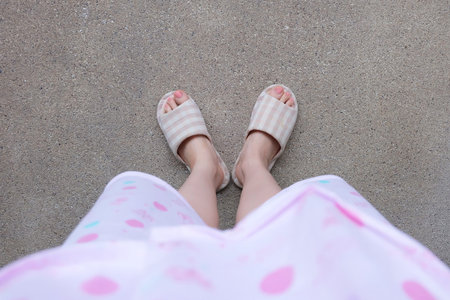 Checkered Warm Slipper with Pink Manicure Nails. Female Legs and Feet in Pink Pajamas and Slippers...