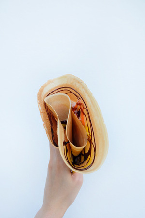 Crepe with Chocolate Sauce Dessert. Woman is Hands Holding Brown Pancake on White Background Great For Any Use.の写真素材