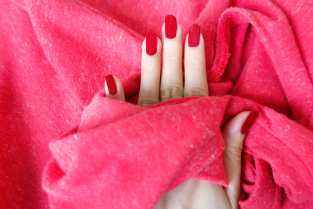 Beautiful Woman Red Nail. Female Hand with Red Nails Manicure Isolated on the Red Fabric Background Great for Any Use.の写真素材