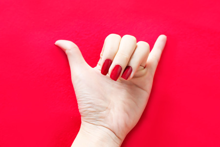 Beautiful Woman Red Nail. Female Hand with Red Nails Manicure Isolated on the Red Fabric Background Great for Any Use.の写真素材