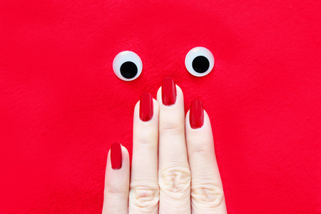 Beautiful Woman Hand with Red Nail. Red Nails Manicure Face with Eye Isolated the Red Fabric Background Great for Any Use.の写真素材