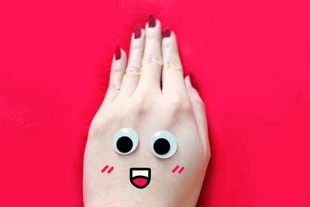 Red Nail Manicure for Valentine. Smile and Funny Face Hand with Red Nails Isolated on the Red Fabric Background Great for Any Use.の写真素材