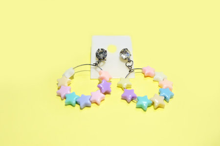 Star Hoop Earring Fashion Accessories. Hoop Earrings with Colorful Star Bead Isolated on Yellow...