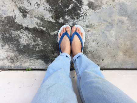Blue Flip Flop Isolated on Cement Floor,Top view. Beautiful Woman Wearing Blue Shoes and Jeans of...