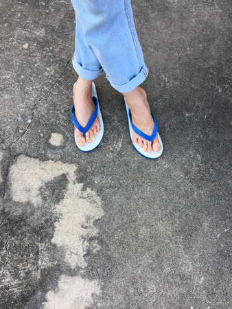 Blue Flip Flop Isolated on Cement Floor,Top view. Beautiful Woman Wearing Blue Shoes and Jeans of Accessory on Concrete Background Great For Any Use.の写真素材