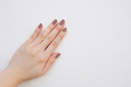 Beautiful Painted Brown Nails. Stylish Cosmetics Trendy Woman Hands Manicure. Hands of Woman with Brown Polish Isolated on White Wall Background Great For Any Useの写真素材