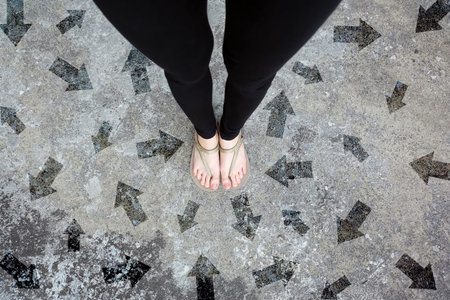 Many Direction Arrow Choices. Gold Shoes Isolated on Concrete Floor,Top View. Woman Standing is Feet...