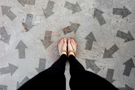 Many Direction Arrow Choices. Gold Shoes Isolated on Concrete Floor,Top View. Woman Standing is Feet Wearing Flip Flop (Sandal) on The Cement Floor Background Great For Any Use.の写真素材