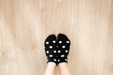 Socks White Color Dot in Black Pattern Top View. Portrait of Beautiful Young Woman Wearing Black Polka Dot Socks on Wooden Floor Background, Vintage Toning. Selfie People Legs and Feet Wear Soft Sock.の写真素材