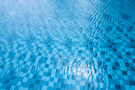 Swimming Pool with Sun Reflection. Surface of Blue and White Pool Water Background of Summer Vacation. Top view of Aqua Ripple on Blue Tiled Texture or Pattern and Abstract. Cyan Ceramic.の写真素材