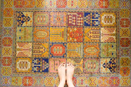 Iran Carpet Texture. Young Woman Feet Standing on Vintage Colorful Carpet with Barefoot.の写真素材