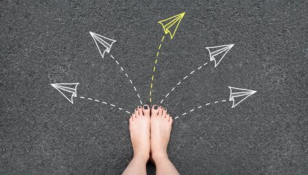 Solution. Selfie woman feet with gray nail polish manicure standing on road with rocket paper and many arrows sign choice. Success, creative and idea concept. Future life. Foot and yellow arrow.の写真素材