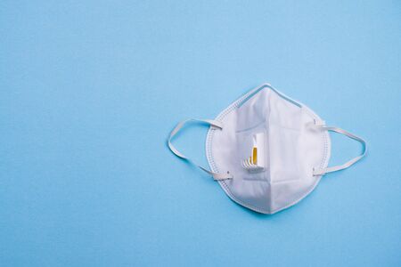 Medical mask isolated on blue background. N95 or white surgical mask for coronavirus outbreak, Covid-19, virus, flu and pollution protection. Prevention health care concept.の写真素材