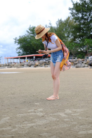 Summer beach background. Portrait young asian woman with a white shirt in vacation travel holiday.の写真素材