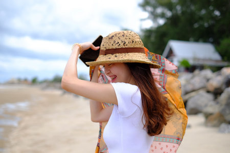 Summer beach background. Portrait young asian woman with a white shirt in vacation travel holiday.の写真素材