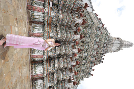 Young Asian woman in traditional Thai costumes at Wat Arun Ratchawararam (the Temple of Dawn) in Bangkok, Thailand.の写真素材