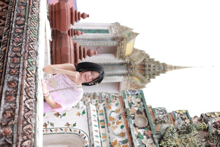 Young Asian woman in traditional Thai costumes at Wat Arun Ratchawararam (the Temple of Dawn) in Bangkok, Thailand.の写真素材