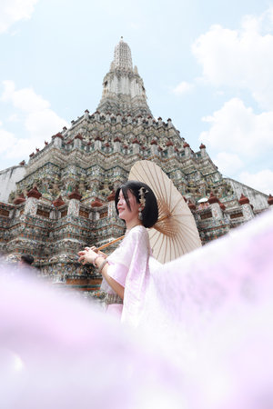Young Asian woman in traditional Thai costumes at Wat Arun Ratchawararam (the Temple of Dawn) in Bangkok, Thailand.の写真素材