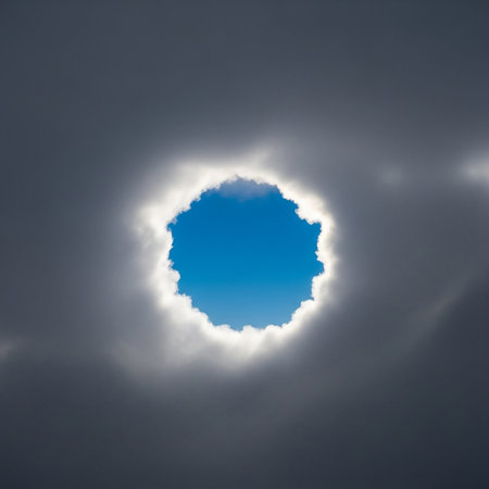 A break in the dark, ominous clouds reveals a vibrant patch of blue sky, framed by a halo of light.の素材