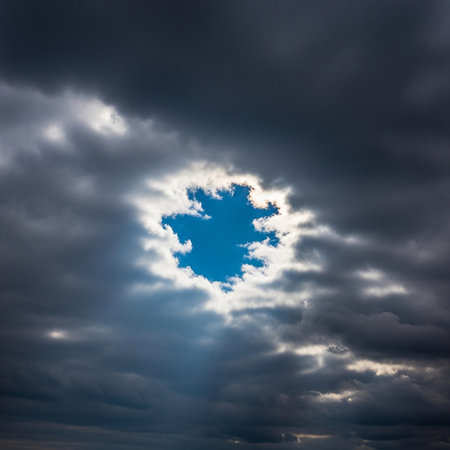 A captivating image of a dramatic sky with dark, ominous clouds surrounding a bright blue hole, creating a striking contrast and visual interest.の素材