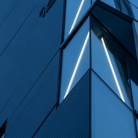 Close-up of a contemporary building exterior featuring sharp angles, reflective glass, and integrated lighting, creating a dynamic geometric design.の素材