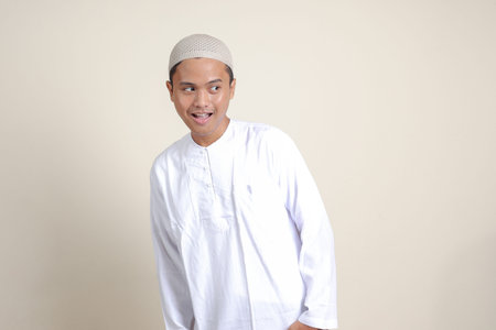Portrait of attractive Asian muslim man in white shirt showing shocked expression and looking aside....