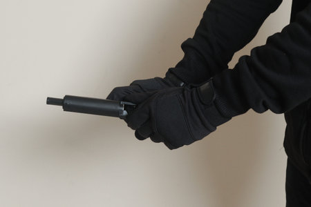 Close up of male hand reloading his pistol after shooting. Isolated image on gray background