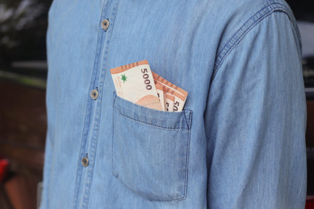 Close up of five thousand rupiah money banknote inside of shirt pocket. Financial and savings...