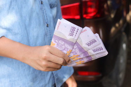 Close up of male hand holding ten thousand rupiah money banknote. Financial and savings concept