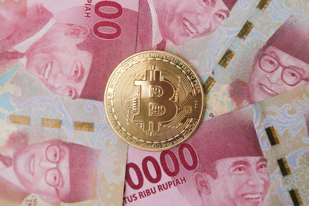 Bitcoin placing on the top of one hundred thousand rupiah bank note. Cryptocurrency trading conceptの写真素材